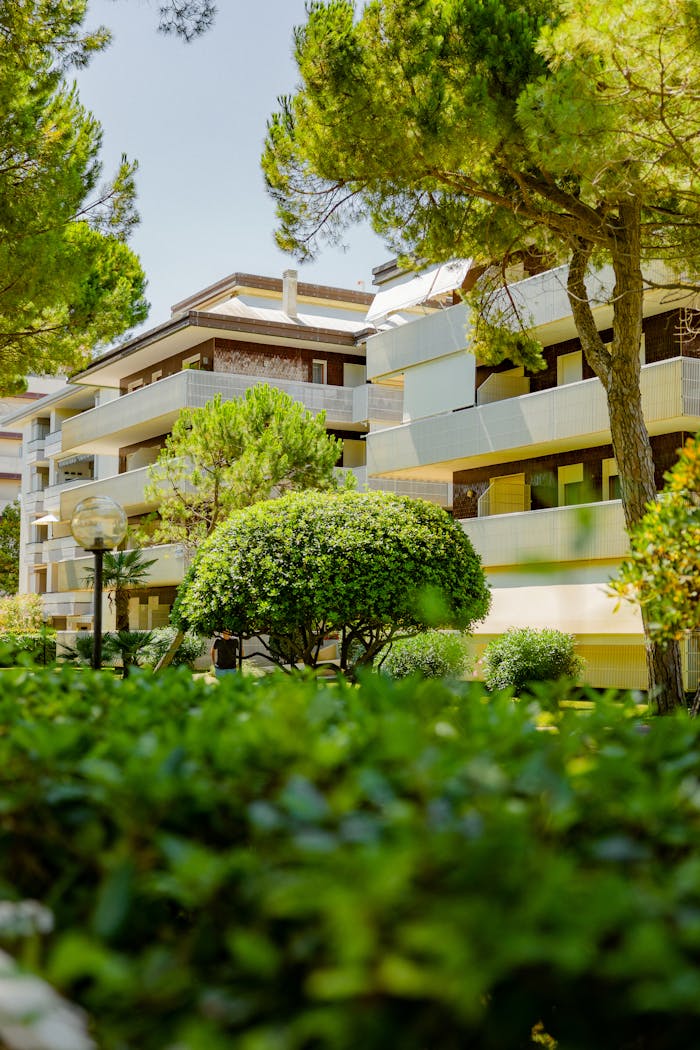 Contemporary apartment building amidst vibrant greenery, capturing a summer vibe.