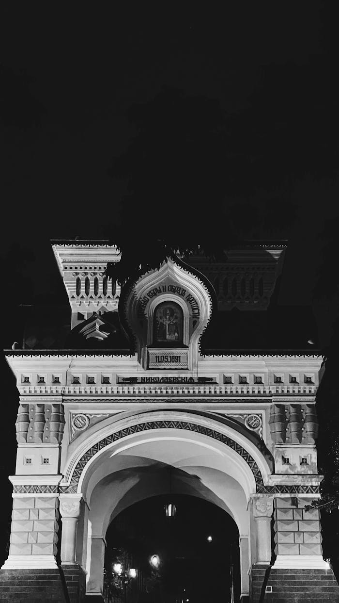 Night view of Vladivostok's Triumphal Arch, a historic landmark lit under the dark sky.